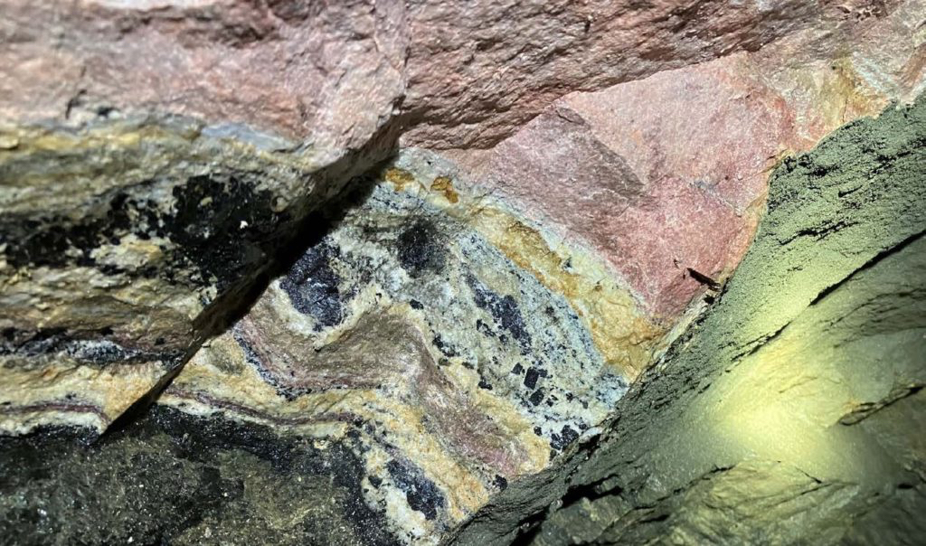 Critical minerals ore showing layered mineralisation in rock face